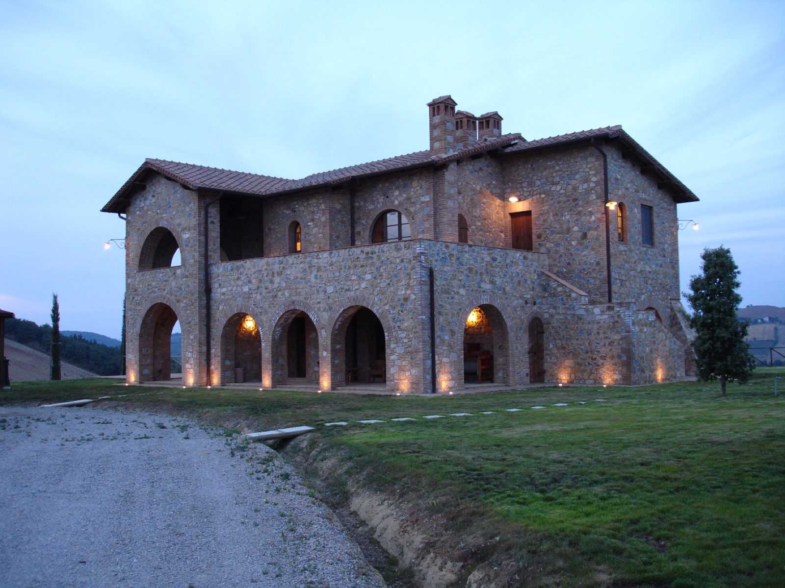 The casale at dusk, its arcades and loggias lit